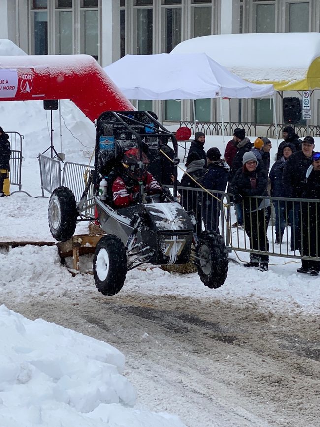 Western Baja SAE race car catching air at a winter competition