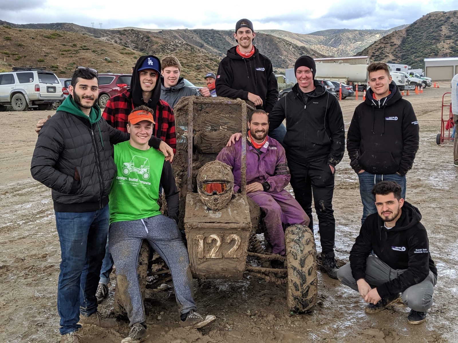 Western Baja SAE team members posing with the muddy race car at competition