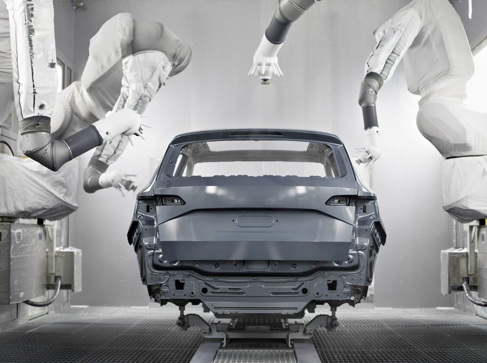 Paint shop robots in protective covers coating an SUV body in a spray booth