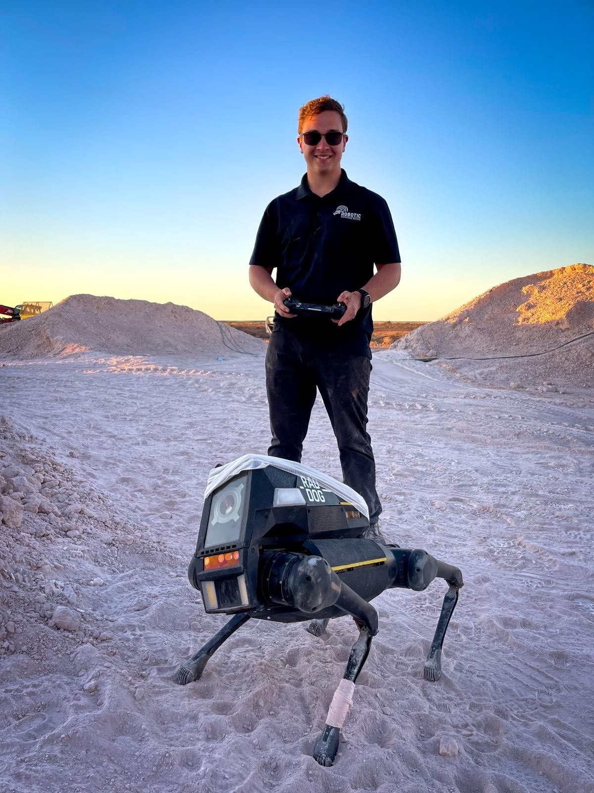 Matthew Margittay operating the RADDOG quadruped robot in the desert at sunset