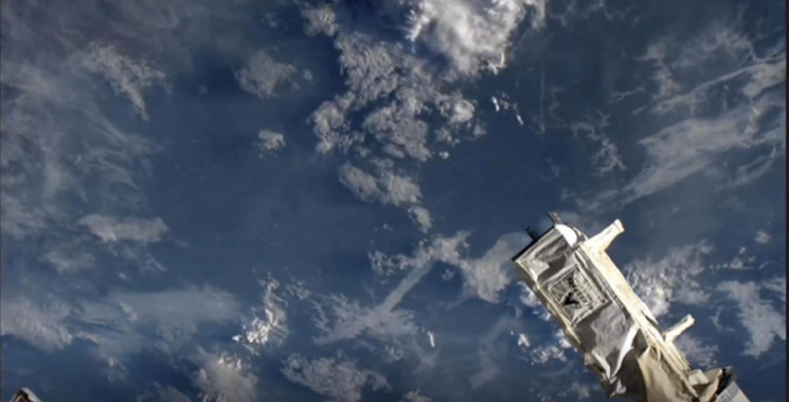 Ukpik-1 deploying from the International Space Station with Earth and clouds below