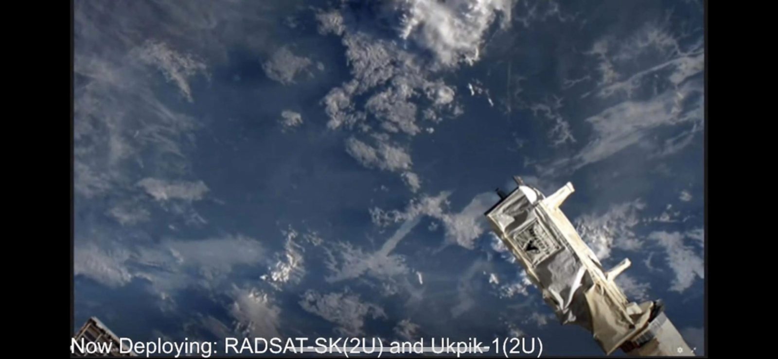 Still from the ISS deployment stream showing Ukpik-1 deploying with Earth below